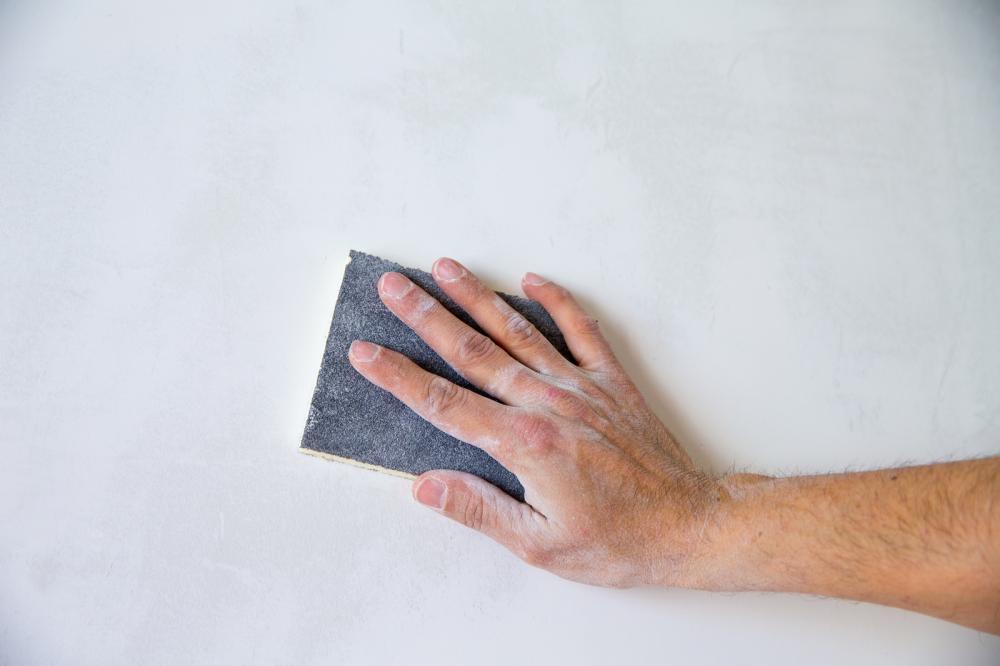 Man using sand paper on a wall to create a smooth surface